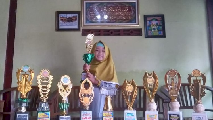 Aishalifa dan piala penghargaan.