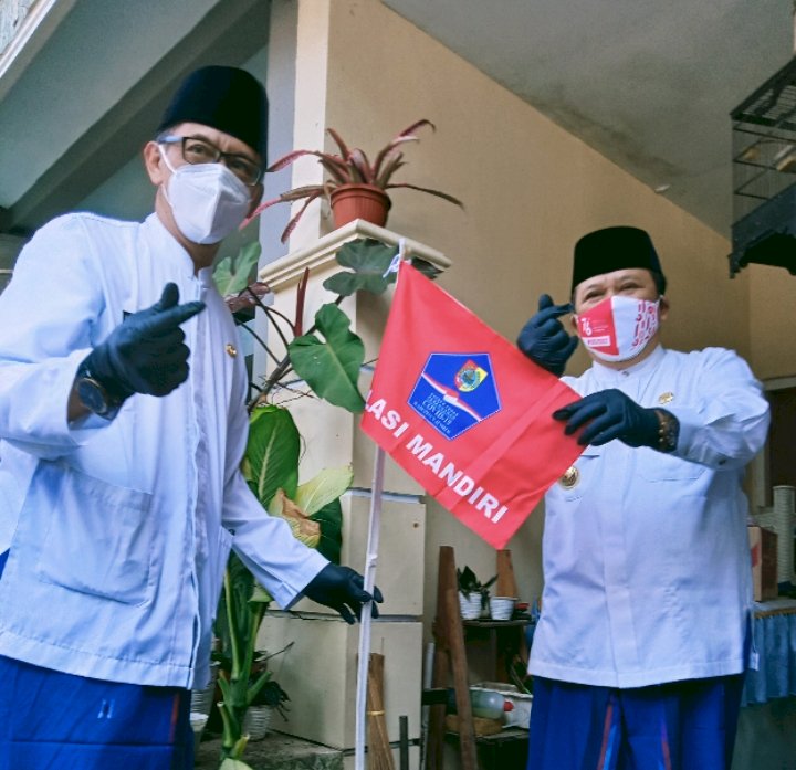 Bupati Jember Hendy Siswanto dan Wakil Bupati Gus Firjaun memasang bendera di rumah warga yang sedang isoman/RMOLJatim