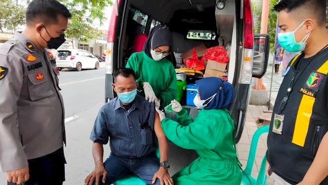 Kasi Dokkes Polresta Banyuwangi, Ipda Sadimun memantau warga yang vaksin saat ada aksi unjuk rasa/RMOLJatim