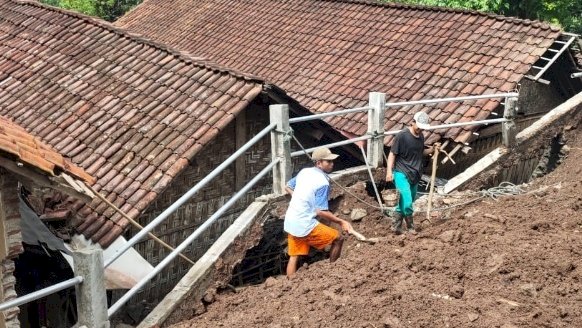 Warga terlihat membersihkan sisa tanah longsor yang menimpa rumah warga. /Ist