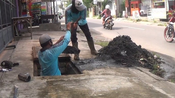 Petugas Dinas PUPR Kota Kediri, melakukan pengerukan drainase