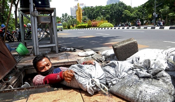 Petugas DSDABM sedang mengangkat lumpur di sepanjang selokan tengah kota Surabaya/Ist