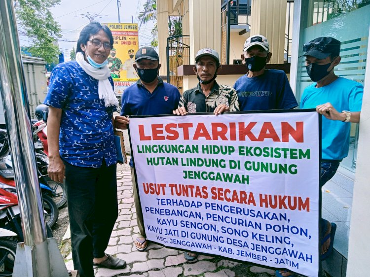 Warga Desa Jenggawah membentangkan banner usai melaporkan kasus penebangan ke Mapolres Jember/RMOLJatim