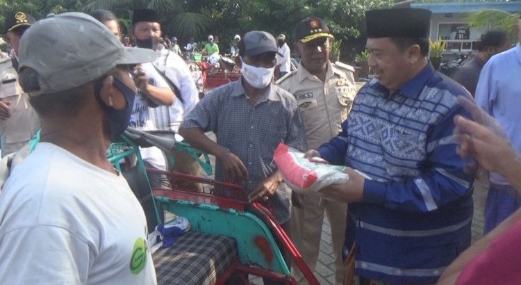 H Warsubi (baju biru) menyerahkan zakat ke pengayuh becak yang mengantre/RMOLJatim