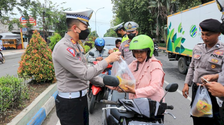 Polisi SatlantasPolres Bangkalan saat membagikan jas hujan dan sembako/RMOLJatim