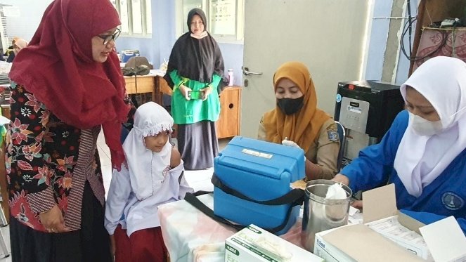 Keterangan foto. Kepsek SD Islam Maryam Lukmawati S.Ag saat mendampingi muridnya melakukan imunisasi