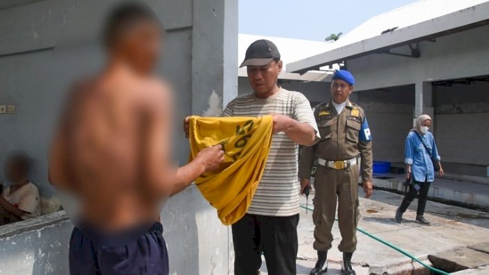 Teks foto: AB memakaikan baju pada ODGJ di Liponsos Surabaya/ist