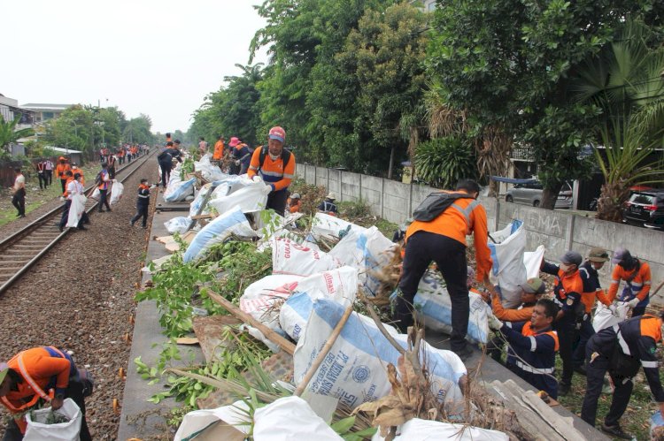 Petugas kereta api membersihkan sampah sampah di samping perlintasan/ ist