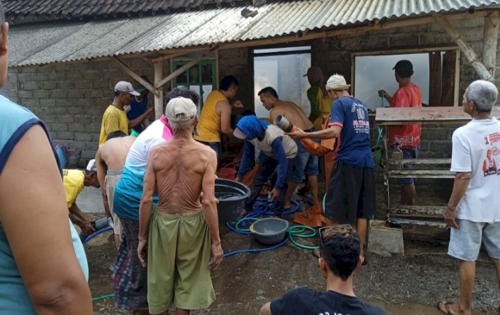 Petugas Damkar dan penyelamatan Ambulu Jember bersama warga saat memadamkan api rumah dan toko milik Atim/RMOLJatim