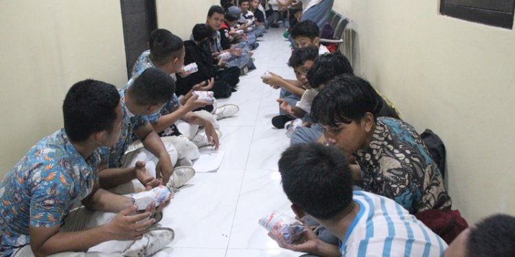 Demonstran yang ditahan polisi tengah menyantap makanan yang dibagikan/Ist