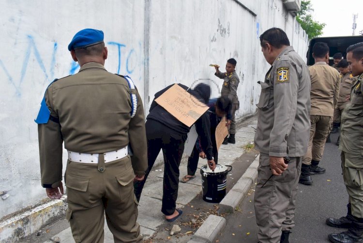 Dua pemuda mengecat ulang tembok yang menjadi sasaran aksi vandalisme/ist