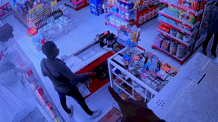 Tampak pria sedang berdiri dekat kasir hendak mencuri hp/ist